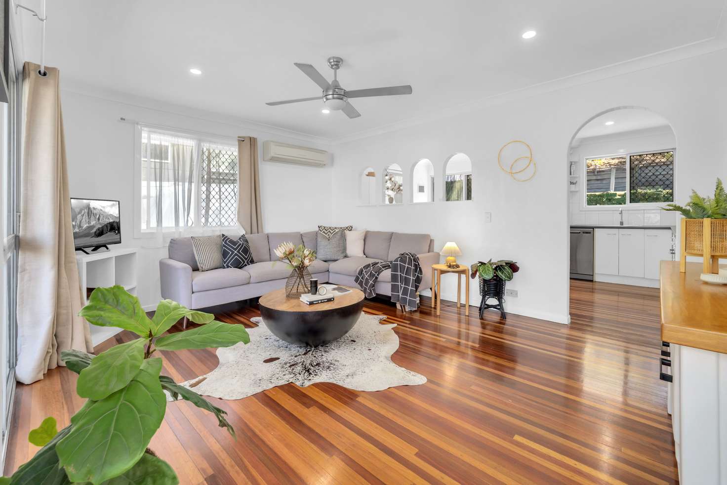 chic modern australian living room with wooden floorboards, bamboo features, neutral colour scheme with a spot of green for colour. 